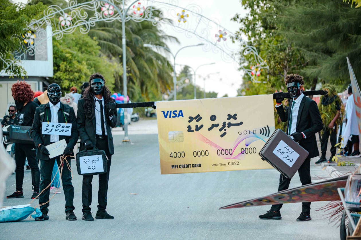ކުޅުދުއްފުށީގައި ކުރިއަށް ގެންދިޔަ މަށިމާލި ޕެރޭޑުގައި ދައްކާލި "ޝޮޕިން ކާޑު". މިއީ އެމްޕީއެލްގެ ކާޑު ބޭނުންކޮށްގެން އެ ކުންފުނީގެ މެނޭޖުމަންޓުގައި ހިމެނިވަޑައިގަންނަވާ ބޭފުޅަކު ވިޔަފާރި ކުރެއްވި ކަމަށް ކުރެވޭ  ތުހުމަތަށް ހާއްސަކޮށް ތައްޔާރުކޮށްފައިވާ މާލިތަކެއް -- ފޮޓޯ: ޖައުފަރު އަލީ