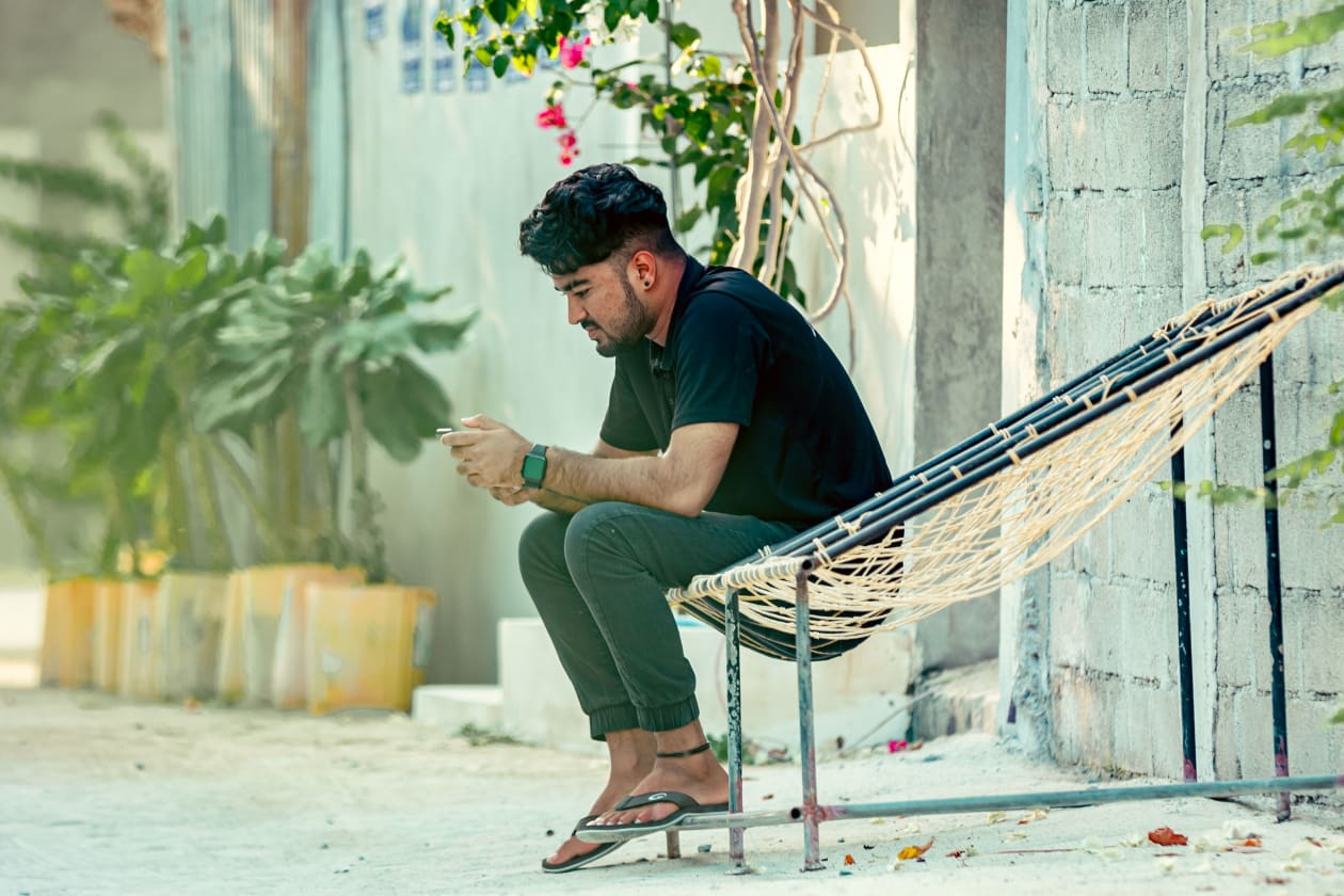 މާފުށީގައި ބިދޭސީއަކި ޖޯލި ފައްޗެއްގައި އިށީނދެލައިގެން އިނދެ އޭނާގެ ފޯނު ބަލަނީ.