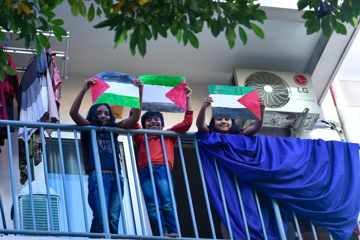 ދިވެހިން ފަލަސްތީނު ރައްޔިތުންނަށް އޮތް ލޯބި ދައްކާލުމުގެ ގޮތުން މިއަދު ބޭއްވި ހަރަކާތް ކުރިއަށްދިޔަ ވަގުތު, ހުޅުމާލޭ ގެއެއްގެ ބެލްކަނީގައި ކުޑަކުދިންތަކެއް ފަލަސްތީނު ދިދަތަކެއް ހިފައިގެން---ފޮޓޯ: ހުސައިން ވަހީދު / އަދަދު
