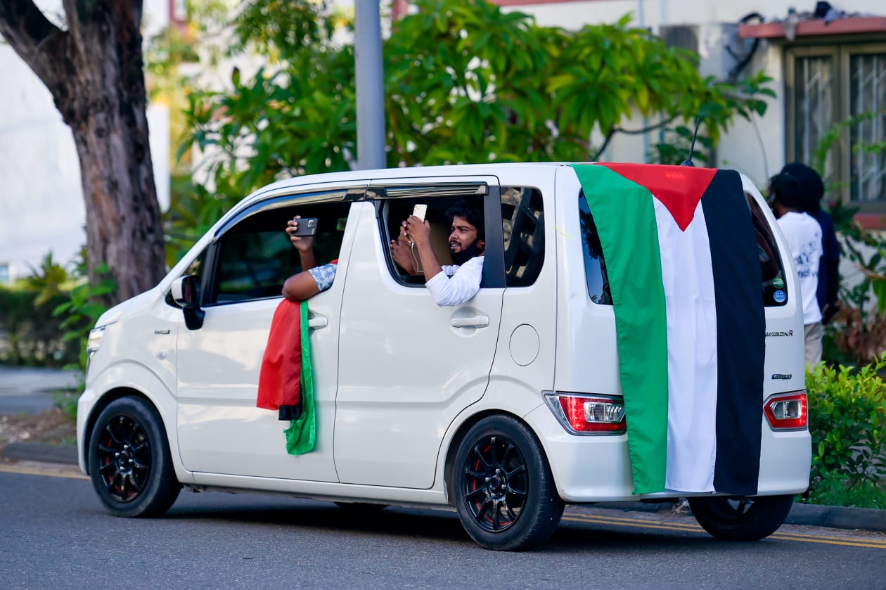 ދިވެހިން ފަލަސްތީނު ރައްޔިތުންނަށް އޮތް ލޯބި ދައްކާލުމުގެ ގޮތުން މިއަދު ބޭއްވި ހަރަކާތް ކުރިއަށްދިޔަ ވަގުތު, ކާރެއްގައި ފަލަސްތީނު ދިދަތަކެއް ޖަހައިގެން ބަޔަކު ދުއްވަނީ---ފޮޓޯ: ހުސައިން ޝަޔާހު / އަދަދު