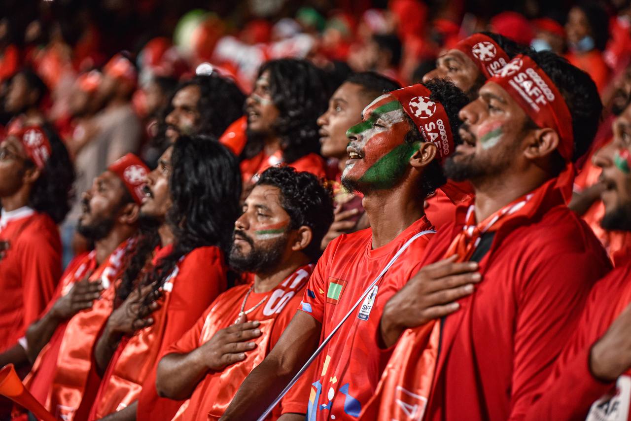 ސާފް ޗެމްޕިއަންޝިޕް 2021ގައި ރާއްޖޭން މެޗް ކުޅުމުގެ ކުރިން ގައުމީ ސަލާމްގައި ސަޕޯޓަރުން ބައިވެރިވަނީ: މުޅި ދަނޑުގައި އެއް އަޑަކުން ގުގުމާލީ "ގައުމީ އެކުވެރިކަން" - ފޮޓޯ: ހުސައިން ޝަޔާހް / އަދަދު